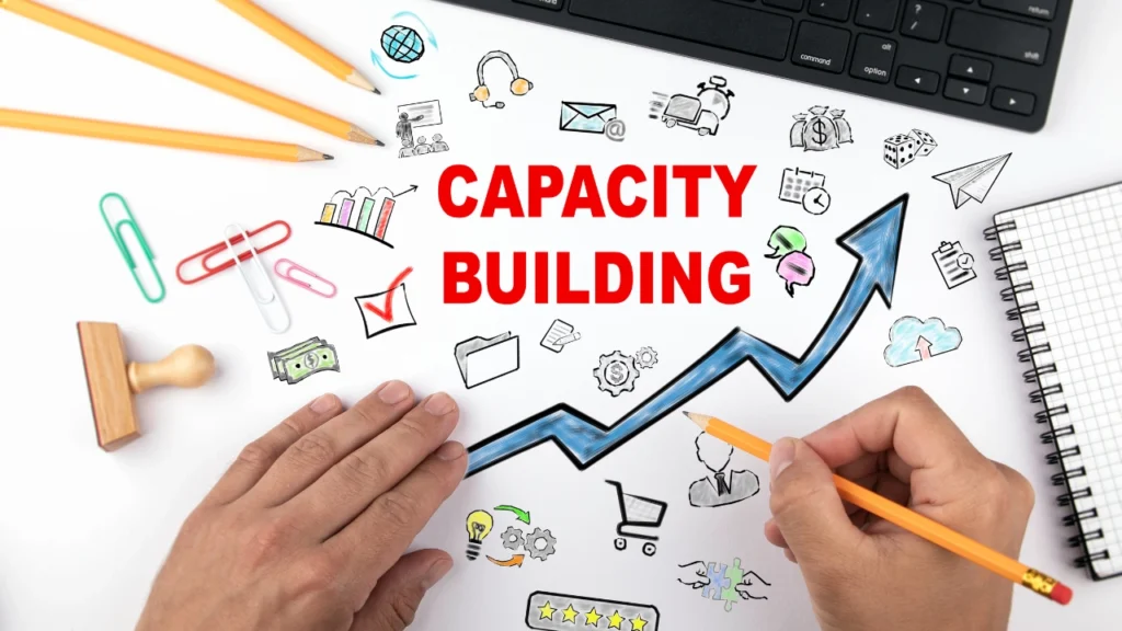 Drawing of an increasing graph with icons & capacity building written in red colour